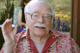 Irving Dayton, an older man with glasses and white hair looks at the camera. 